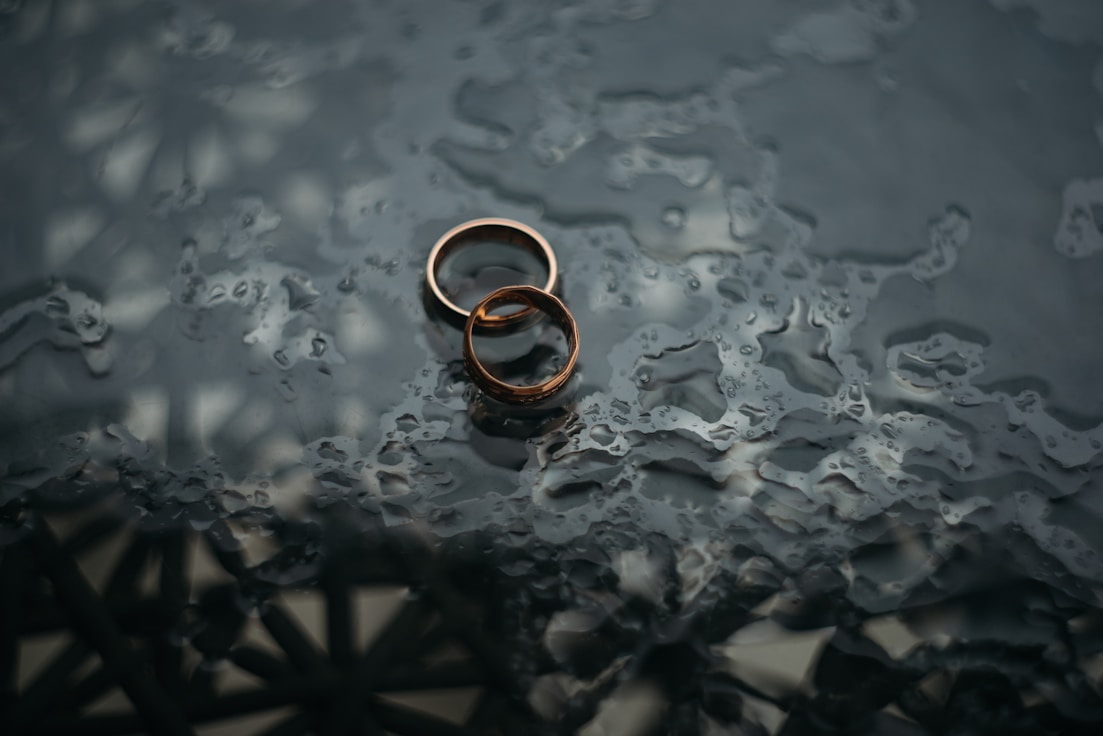 Two entwined gold rings on dewy table, representing marriage dissolution and prenuptial agreement services by specialist divorce lawyers.