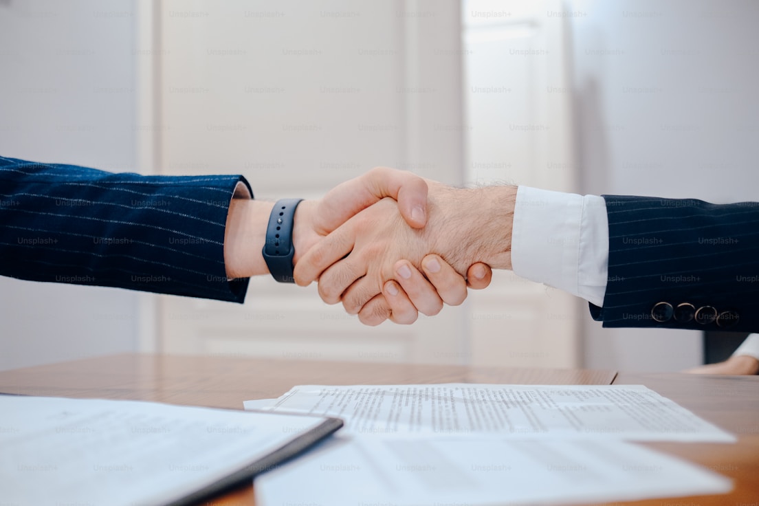Professional handshake between solicitors and client over contracts on desk, symbolizing trust in family law consultations and agreements.